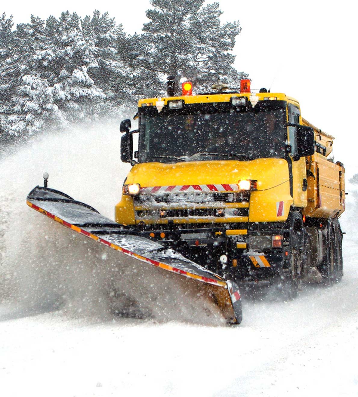Yellow gritting vehicle with snow plough in winter conditions